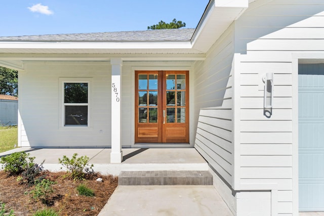 property entrance featuring a porch, french doors, roof with shingles, and a garage