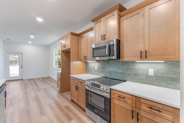 kitchen with tasteful backsplash, baseboards, stainless steel appliances, light countertops, and light wood-type flooring