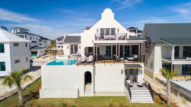 rear view of house featuring a patio, a balcony, fence, a pool with connected hot tub, and stucco siding