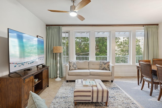 living area with light tile patterned floors, baseboards, and ceiling fan