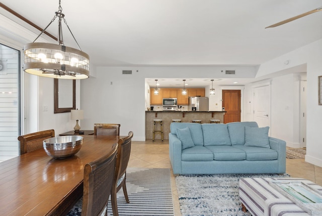 living room featuring light tile patterned floors, visible vents, baseboards, and a chandelier