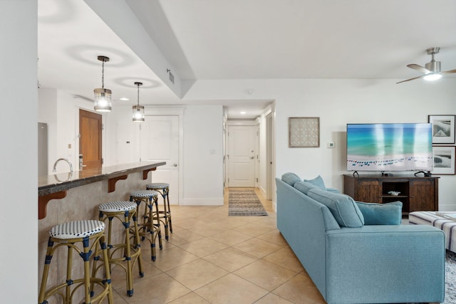 living room with light tile patterned floors, visible vents, baseboards, and ceiling fan