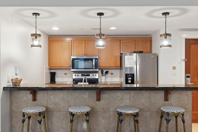 kitchen featuring a kitchen bar, pendant lighting, tasteful backsplash, and stainless steel appliances