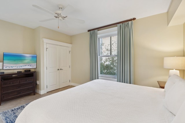 tiled bedroom with a ceiling fan, baseboards, and a closet