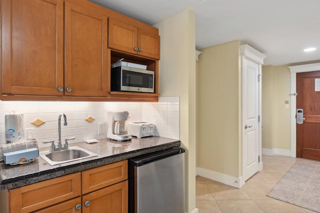 kitchen with tasteful backsplash, stainless steel microwave, dishwasher, light tile patterned flooring, and a sink