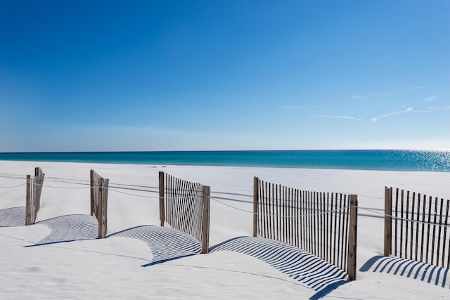 unfurnished bedroom featuring a view of the beach and a water view