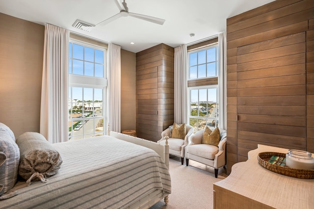 bedroom with visible vents, multiple windows, wood walls, and carpet floors