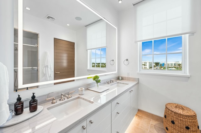 bathroom with double vanity, visible vents, and a sink