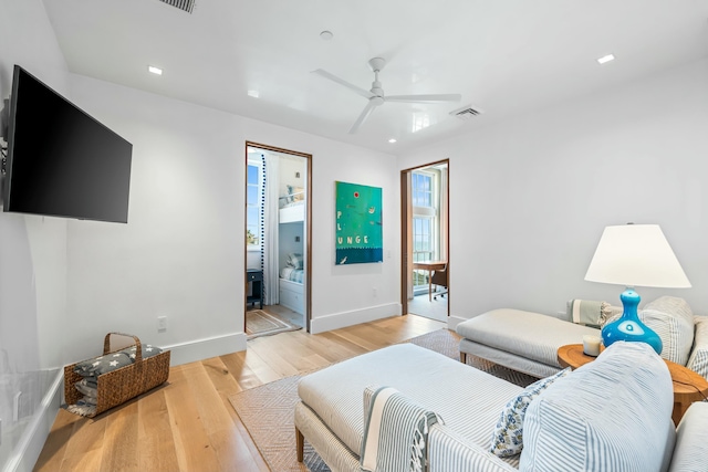 living room with visible vents, ceiling fan, baseboards, and light wood-style floors