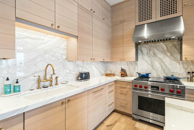 kitchen featuring light brown cabinets, a sink, designer stove, exhaust hood, and tasteful backsplash