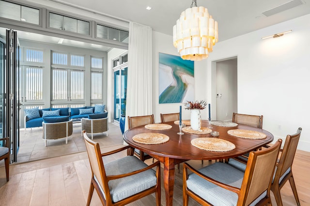 dining space featuring light wood-style flooring, visible vents, and a chandelier