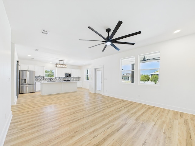 unfurnished living room with baseboards, light wood-style flooring, visible vents, and a ceiling fan