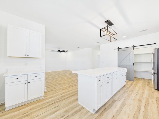 spacious closet featuring a ceiling fan, light wood-style flooring, and a barn door