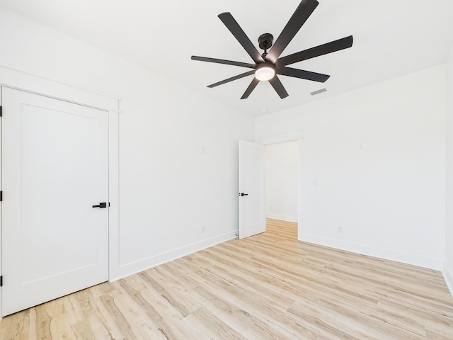 spare room with a ceiling fan, wood finished floors, visible vents, and baseboards