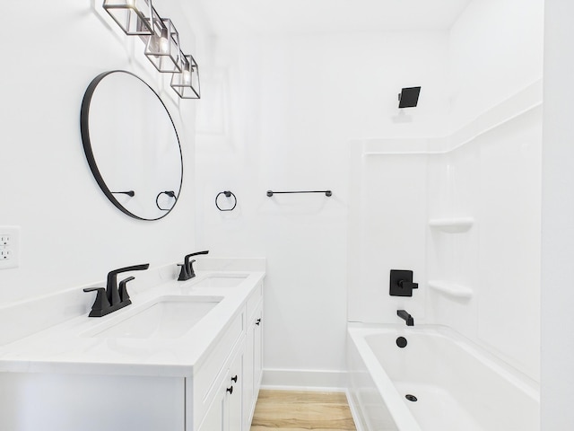 bathroom featuring double vanity, shower / washtub combination, a sink, and baseboards