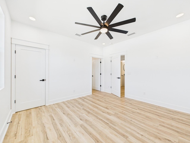 spare room featuring baseboards, a ceiling fan, visible vents, and light wood-style floors