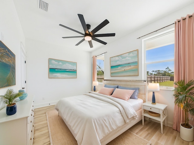 bedroom featuring light wood-style flooring, visible vents, ceiling fan, and baseboards