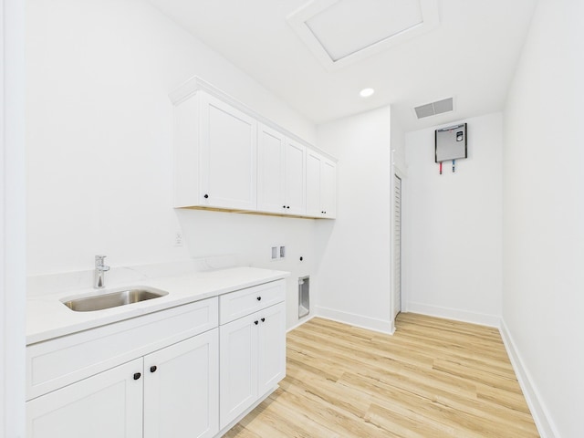 clothes washing area with cabinet space, visible vents, light wood-style floors, washer hookup, and a sink