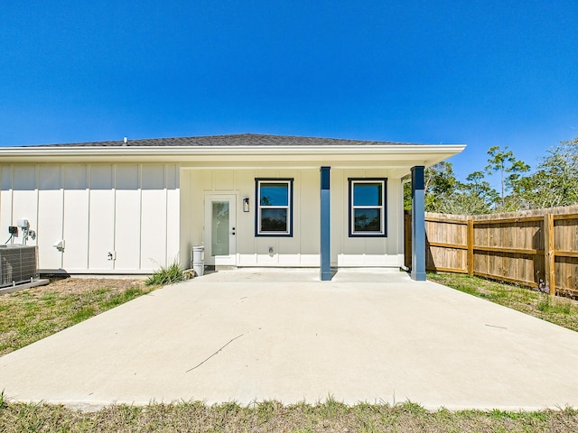 view of front of house with board and batten siding, cooling unit, and fence