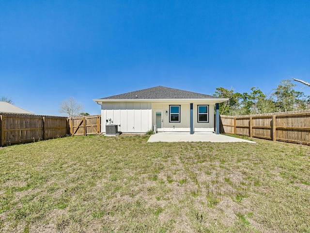 back of property with a fenced backyard, a yard, central air condition unit, a patio area, and board and batten siding