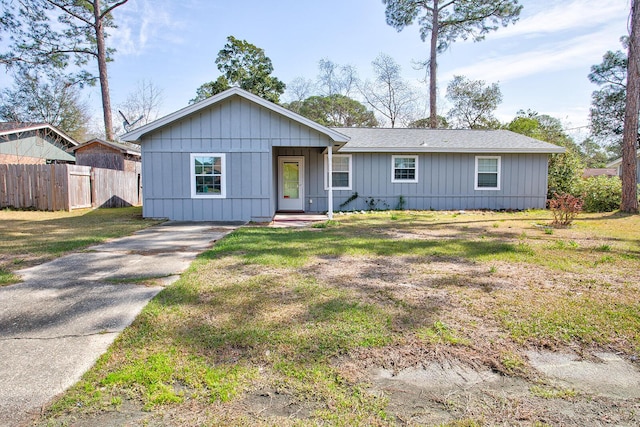 view of front of house featuring fence, a front lawn, and board and batten siding