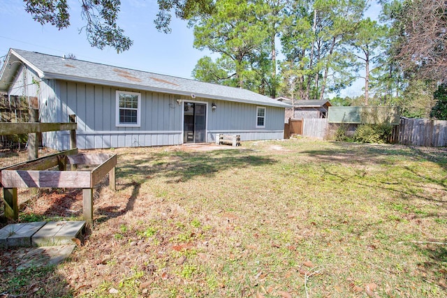 back of property featuring a lawn and fence