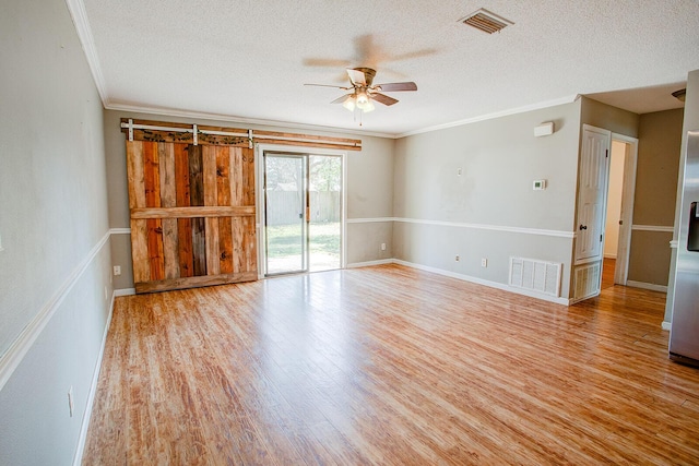 spare room featuring ornamental molding, visible vents, a textured ceiling, and wood finished floors