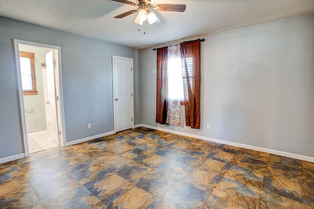 spare room with a textured ceiling, ceiling fan, and baseboards