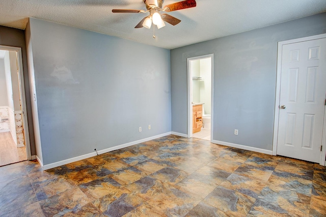 unfurnished bedroom with stone finish floor, ceiling fan, a textured ceiling, ensuite bath, and baseboards