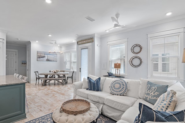 living area with a healthy amount of sunlight, visible vents, crown molding, and ceiling fan with notable chandelier