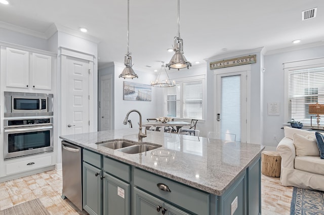 kitchen with visible vents, appliances with stainless steel finishes, a kitchen island with sink, gray cabinetry, and a sink