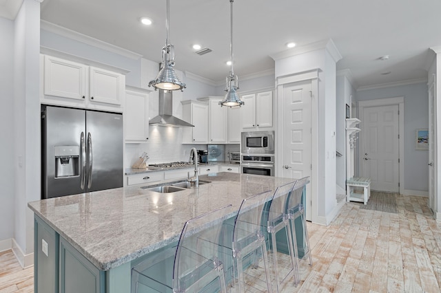 kitchen featuring visible vents, wall chimney exhaust hood, appliances with stainless steel finishes, crown molding, and a sink