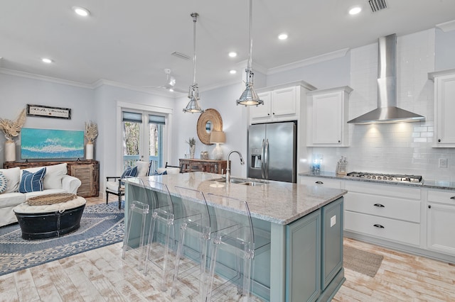 kitchen featuring light stone counters, stainless steel appliances, a sink, wall chimney range hood, and french doors