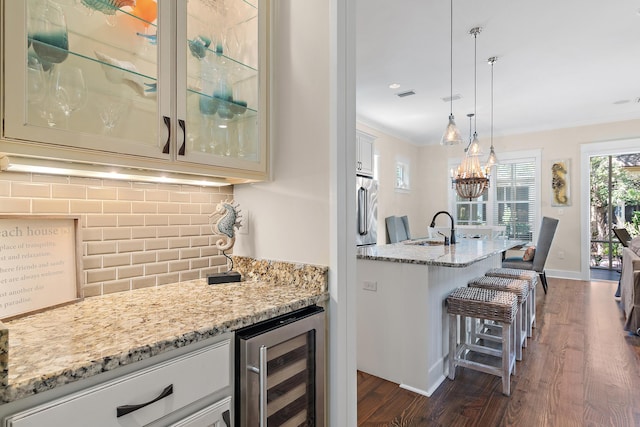 bar with wine cooler, decorative backsplash, ornamental molding, a sink, and high end refrigerator