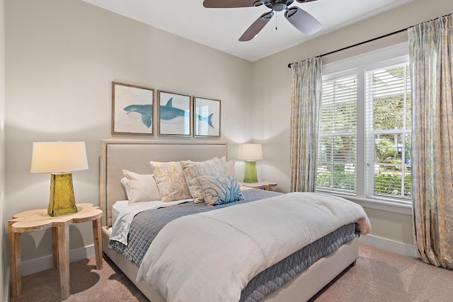 carpeted bedroom with multiple windows, a ceiling fan, and baseboards