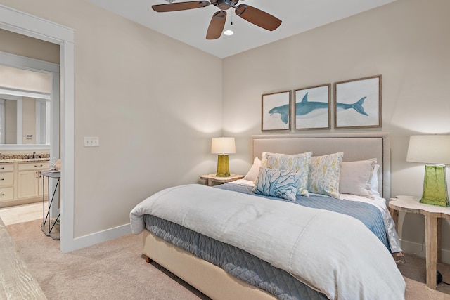 bedroom with light carpet, baseboards, ceiling fan, ensuite bathroom, and a sink