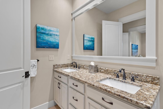 bathroom with double vanity, baseboards, and a sink