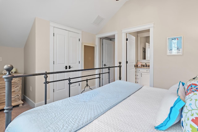 carpeted bedroom with lofted ceiling, a closet, visible vents, connected bathroom, and baseboards