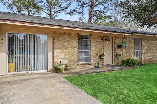 property entrance with a yard and brick siding