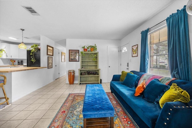 living room with visible vents, a textured ceiling, and light tile patterned flooring