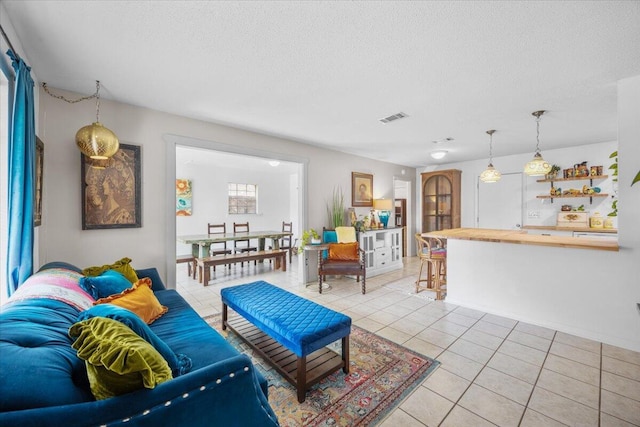 living area featuring visible vents, a textured ceiling, and light tile patterned flooring