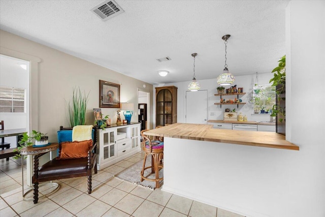 kitchen with butcher block counters, visible vents, white dishwasher, and a textured ceiling