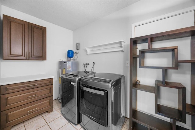 washroom with laundry area, light tile patterned floors, washing machine and clothes dryer, a textured ceiling, and water heater