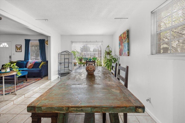 tiled dining room with baseboards, visible vents, and a textured ceiling