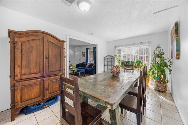 dining area with a textured ceiling, light tile patterned flooring, and visible vents