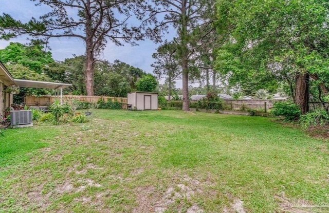 view of yard with central air condition unit, a fenced backyard, a storage unit, and an outdoor structure