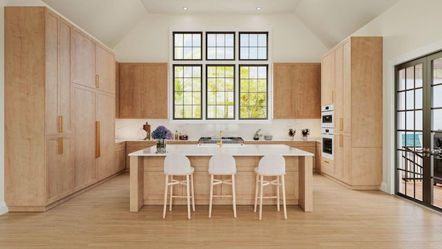 kitchen with a kitchen bar, a center island, light brown cabinets, and light countertops