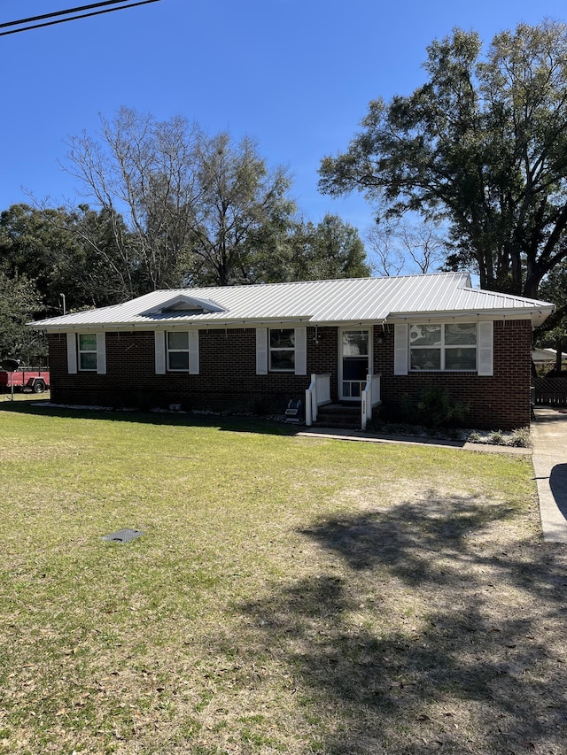 ranch-style home featuring metal roof, a front lawn, and brick siding