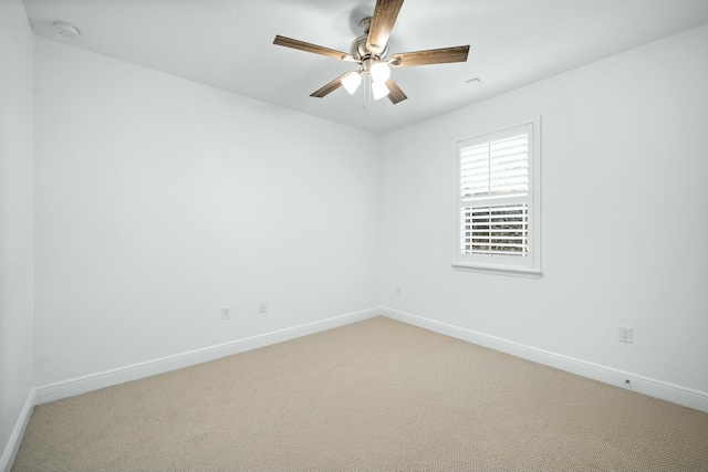 spare room featuring baseboards, light carpet, and a ceiling fan