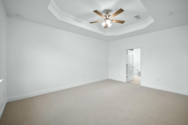 spare room featuring visible vents, ceiling fan, a tray ceiling, ornamental molding, and light carpet